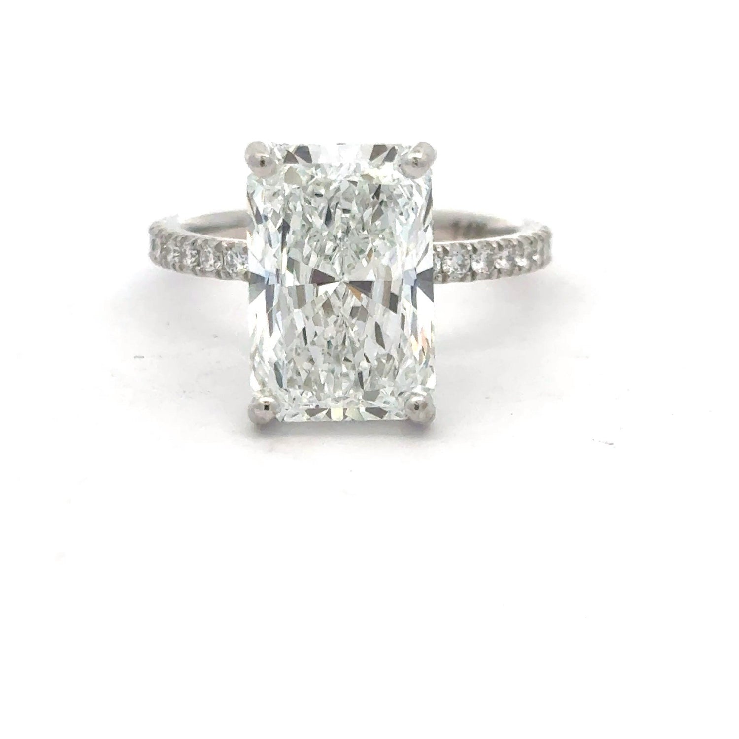 14K white gold engagement ring with a 5.09 carat radiant cut lab grown diamond center stone, hidden halo, and diamonds along three quarters of the shank