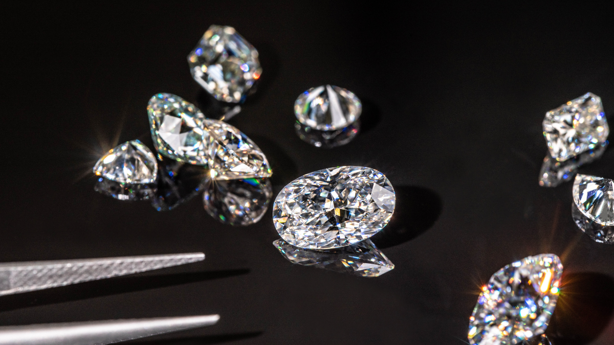 Lab grown diamonds on a black surface with tweezers