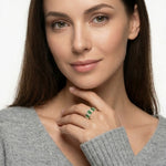 Woman wearing a green gemstone ring on a neutral background